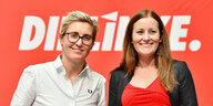 Susanne Hennig-Wellsow und Janine Wissler gemeinsam vor einer roten Wand mit dem Parteilogo von Die Linke