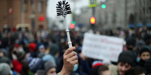 Demonstranten halten eine Klobürste hoch