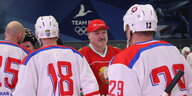 Alexander Lukaschenko mit drei Eishockeyspielern in voller Montur