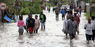 Menschen waten durch Wasser auf einer Straße in Mosambik