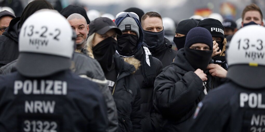 Hooligans stehen vor zwei Polizisten