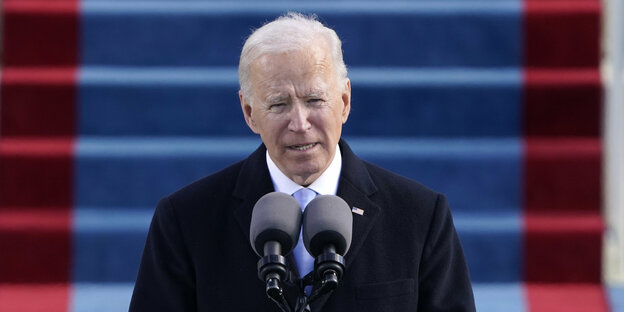 Joe Biden steht vor einer Treppe am Rednerpult