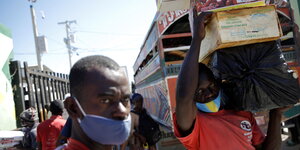 Ein Mann mit Mund-Nase-Schutz trägt Waren an der Grenze von Haiti und der Dominikanischen Republik