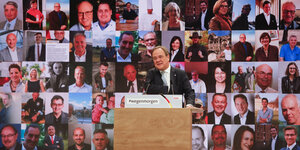 Der CDU-Vorsitzende Laschet am Rednerpult vor einer Fototapete mit Bildern vieler Menschen