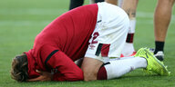 Fußballer kniet auf den Boden und vergräbt sein Gesicht in den Händen