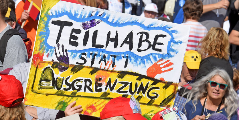 Menschen bei einer Demonstration zeigen ein Plakat mit der Aufschrift "Teilhabe statt Ausgrenzung"