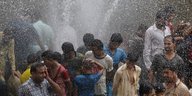 Pakistani im Sprühregen einer lecken Wasserleitung