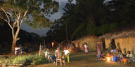 Abendstimmung in einem Dorf mit kleinen Häusern, Menschen versammeln sich enstspannt