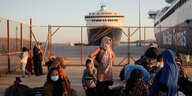 Geflüchtete nach der Ankunft auf dem griechischen Festland - Frauen und Kinder, im Hintergrund eine Fähre