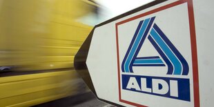 Wegweiser Aldi - Supermarkt. Ein gelber LKW fähr vorbei