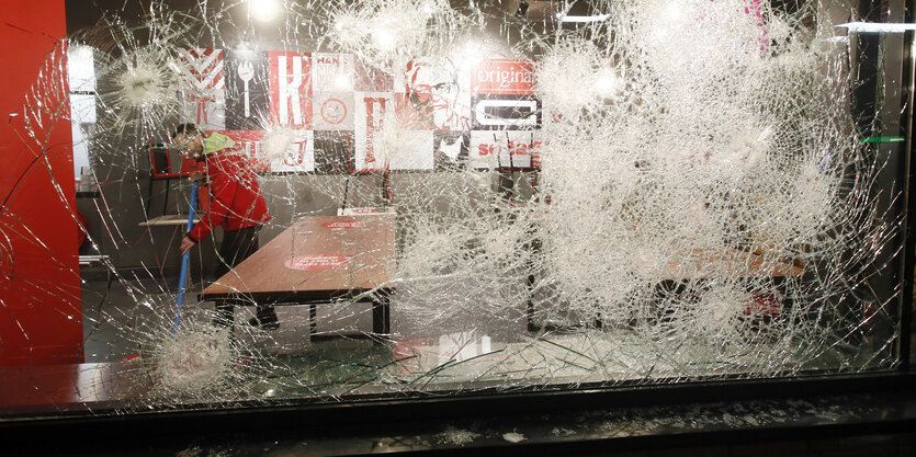 Ein Mann ist beim Aufräumen durch das beschädigte Glas in einem Fast-Food-Restaurant zu sehen, das bei Protesten gegen eine landesweite Ausgangssperre eingeschlagen wurde.