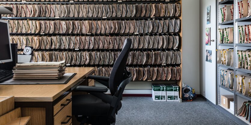 Blick in das Büro einer Behörde, mit Akten an der Wand und einem Schreibtisch mit Bürostuhl