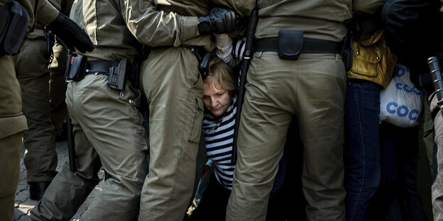 Polizisten in Minsk drängen Demonstrierende zurück. Eine Frau am Boden ist zwischen Polizisten-Beinen zu sehen.
