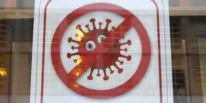 Piktogramm mit durchgestrichenem Corona Virus hängt an einert Glastür