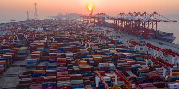 Ein Containerhafen in Shanghai mit unzähligen Conainern während des Sonnenuntergangs