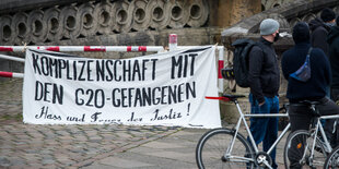 Ein Protest-Transparent hängt vor dem Hamburger Gericht, zwei Personen stehen daneben