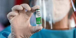 Eine Medizinische fachkraft hält eine AstraZeneca Impfdose in der Hand und trägt dabei Schutzhandschuhe