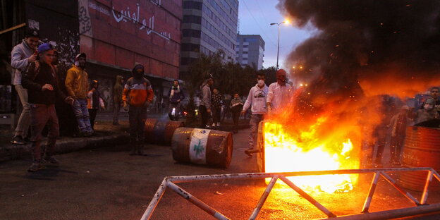 Demonstranten in Tripolis vor einer brennenden Mülltonne