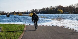 Ein Radfahrer fährt auf einem überschwemmten Radweg