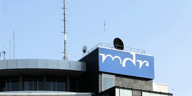 MDR-Logo an einem grauen Gebäude, vor blauem Himmel