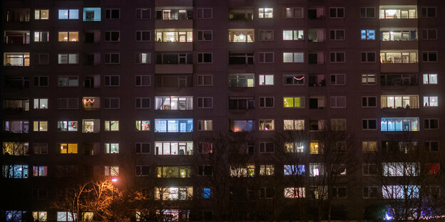Viele Fenster an einem Mehrfamilienhaus sind am Abend erleuchtet