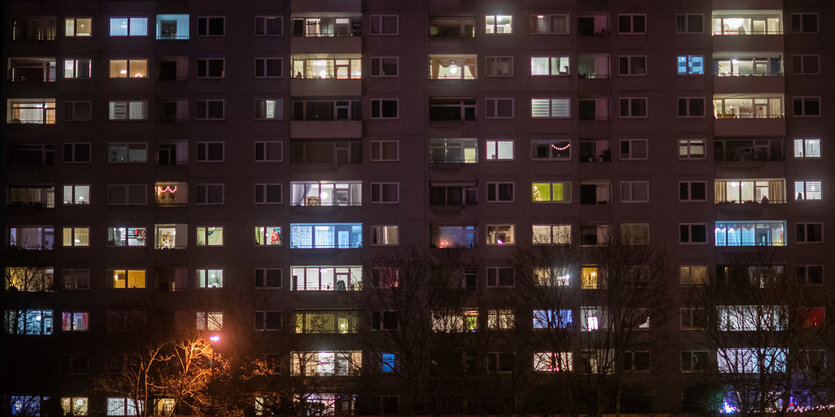 Viele Fenster an einem Mehrfamilienhaus sind am Abend erleuchtet