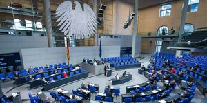 Plenarsitzung im Bundestag - Abgeordnete sitzen an ihren Plätzen und hören dem Redner am Pult zu