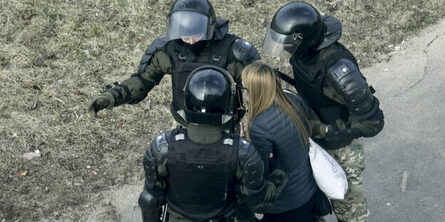 eine demonstrantin wird von 3 Poliziten festgenommen