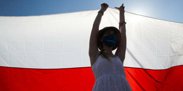 Eine Demonstrantin in Minsk hebt eine große, weiße Flagge in die Höhe