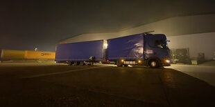 Ein blauer LKW steht in der Nacht auf einem Parkplatz