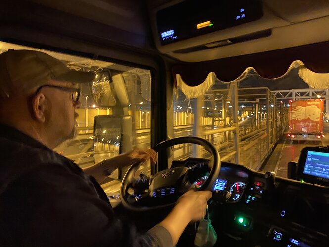 Ein Mann sitzt am Steuer seines LKW, draußen ist es dunkel