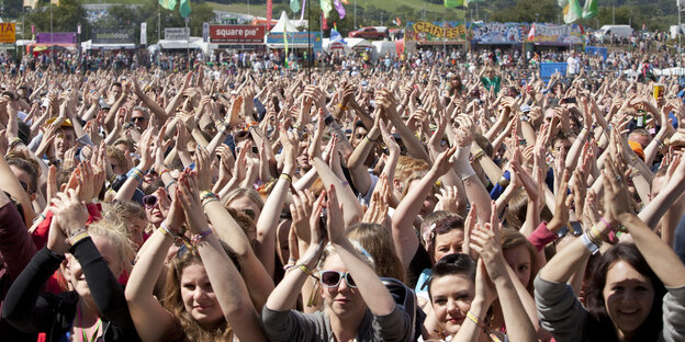 Menschen sind bei einem Konzert und halten ihre Hände in die Luft