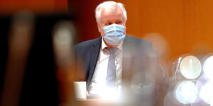 Horst Seehofer trägt einen Mundschutz und sitzt beim wöchentlichen Konferenztreffen mit Merkel