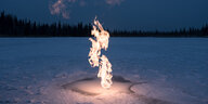 Ein Flamme, die aus einer schneebedeckten Eisfläche emporsteigt