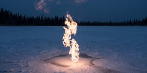 Ein Flamme, die aus einer schneebedeckten Eisfläche emporsteigt