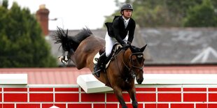 Ein Springreiter überspringt mit seinem Pferd eine Mauer