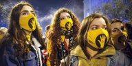 Demonstrantinnen mit gelben Masken mit "Free SzFE"-Slogan.