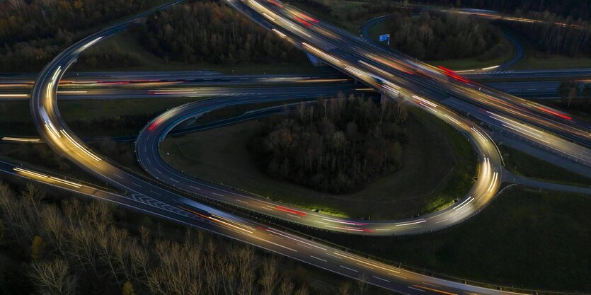 Autobahnschleife von oben bei Nacht, Autolichter nur verschwommen zu sehen