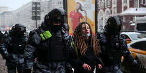 Viele behelmte Polizistenführen eine verhaftete Frau ab