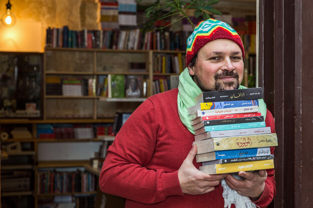 Ein Mann hält einen Stapel arabischer Bücher in die Kamera und lächelt Ein Mann hält einen Stapel arabischer Bücher in die Kamera und lächelt