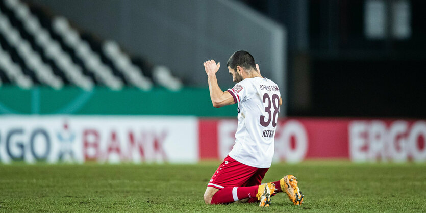 Fußballspieler kniet auf dem Rasen