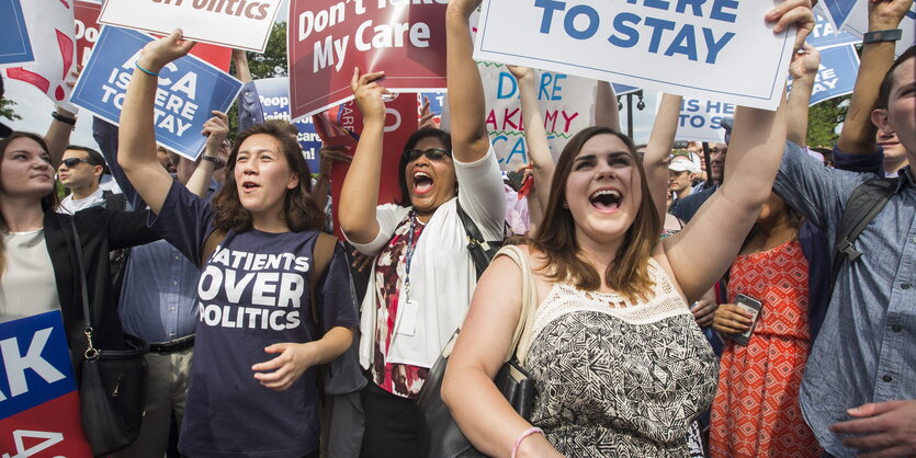 Jubelnde Menschen mit Transparenten für Obamacare