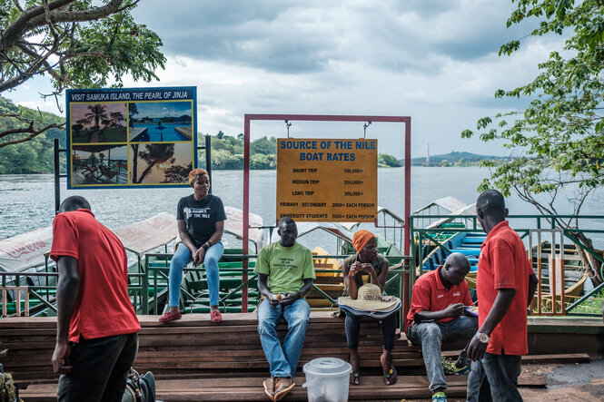 Menschen sitzen an der Anlegestelle am Ufer des Victoriasees