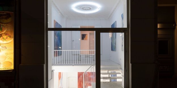 Eine abendliche Außenansicht durch die Fenster der Galerie Blake & Vargas mit abstrakten Gemälden der Künstlerin Agne Juodvalkyte