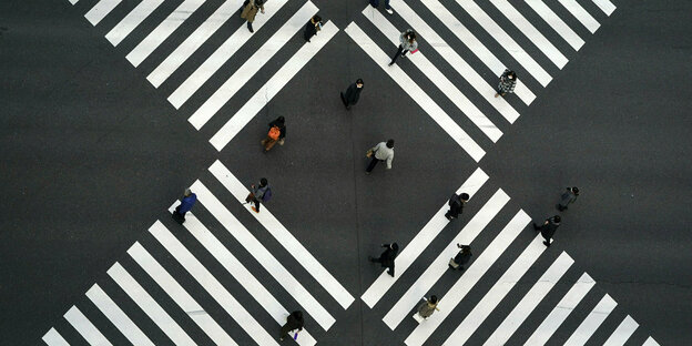 Menschen in Tokio tragen Mund-Nasenschutz und laufen über einen kreufförmig angeordneten Zebrastreifen