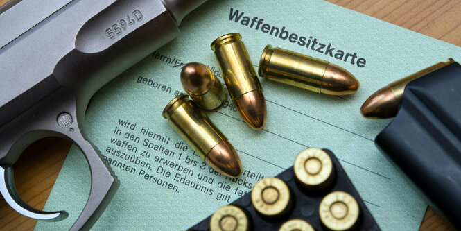 Eine Kaliber 9 mm Pistole, Patronen und ein Magazin liegen auf einer Waffenbesitzkarte.