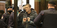 Alexei Nawalny mit Handschallen im Gerichtssaal - neben ihm Polizisten