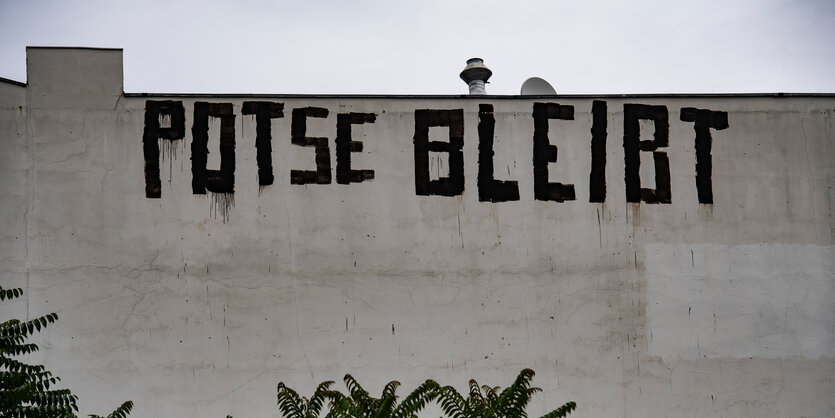 Auf einer großen grauen Hauswand steht ein großer Schriftzug: Potse bleibt