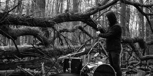 Auf einem schwarzweißen Foto wird ein Schlagzeug im Wald aufgebaut