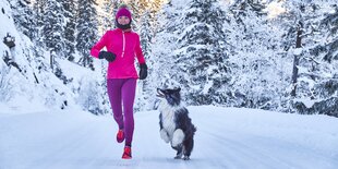 Joggerin mit Hund im Schnee